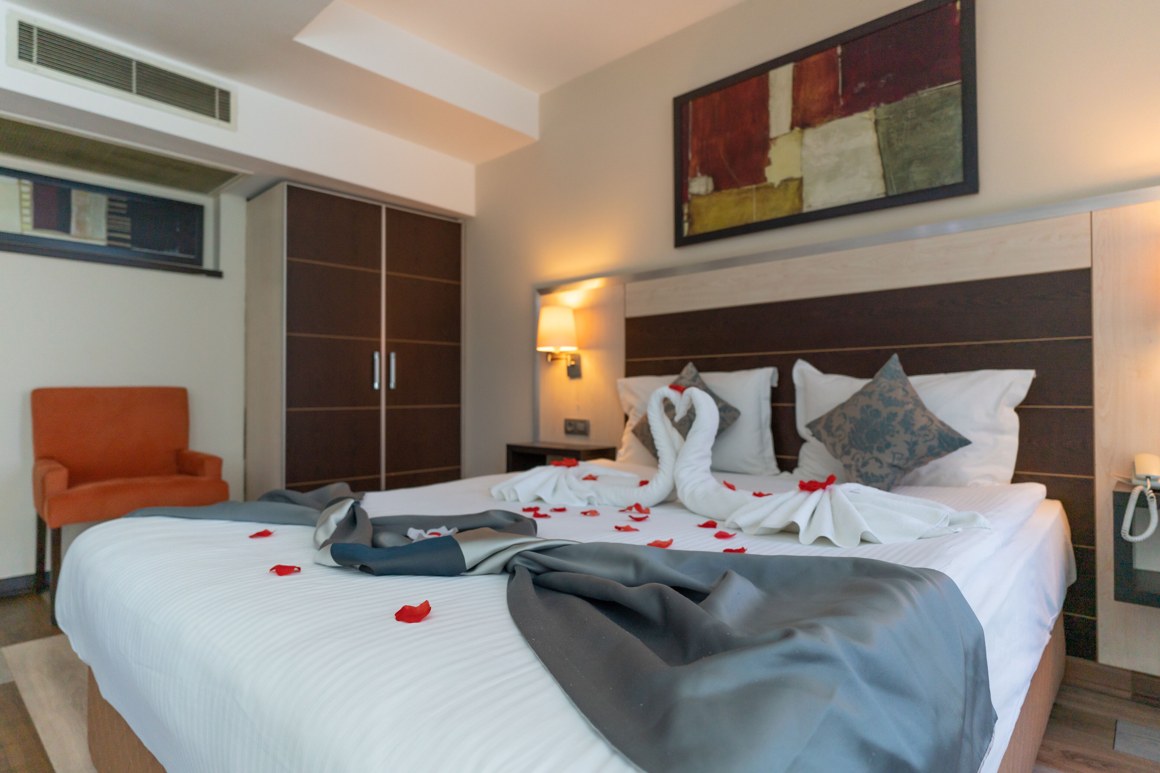 Una habitación de hotel con una cama grande, una mesita de noche, una silla y un cuadro en la pared.