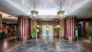 A lobby with a tiled floor, wooden columns, and hanging lamps. - Colony Hotel (Rome)