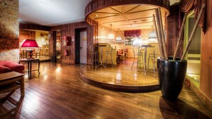 A spacious room with a wooden floor, a red lamp, a large black vase, and a curved wooden wall. - Colony Hotel (Rome)