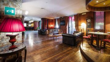 Un'ampia hall con pavimento in legno, zone relax, una lampada rossa e una sveglia.