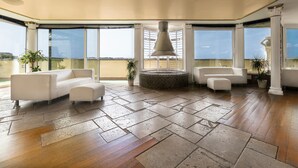 A spacious living area with a large window, a round table, and two white sofas. - Colony Hotel (Rome)