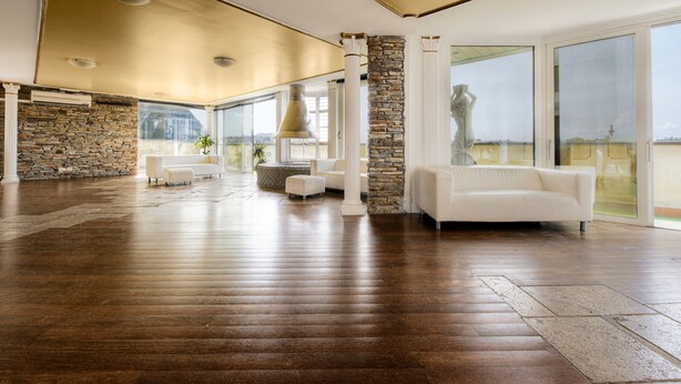 A spacious living room with a stone wall, large windows, and a white sofa. - Colony Hotel (Rome)