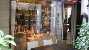 An outdoor seating area with a table and chairs, a wine barrel, and a wine shop sign. - Hotel Da Cesare (Stresa)