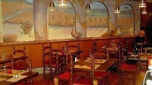 A restaurant interior with wooden tables and chairs, a large mural on the wall, and hanging pendant lights. - Hotel Da Cesare (Stresa)