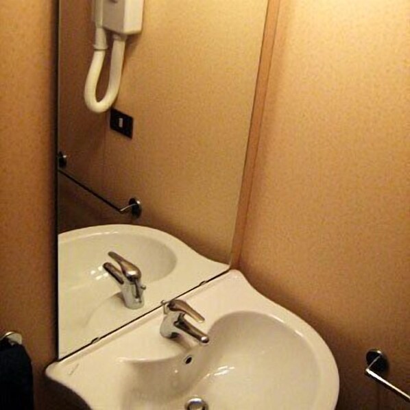 A bathroom with a white sink, a mirror, and a telephone mounted on the wall.