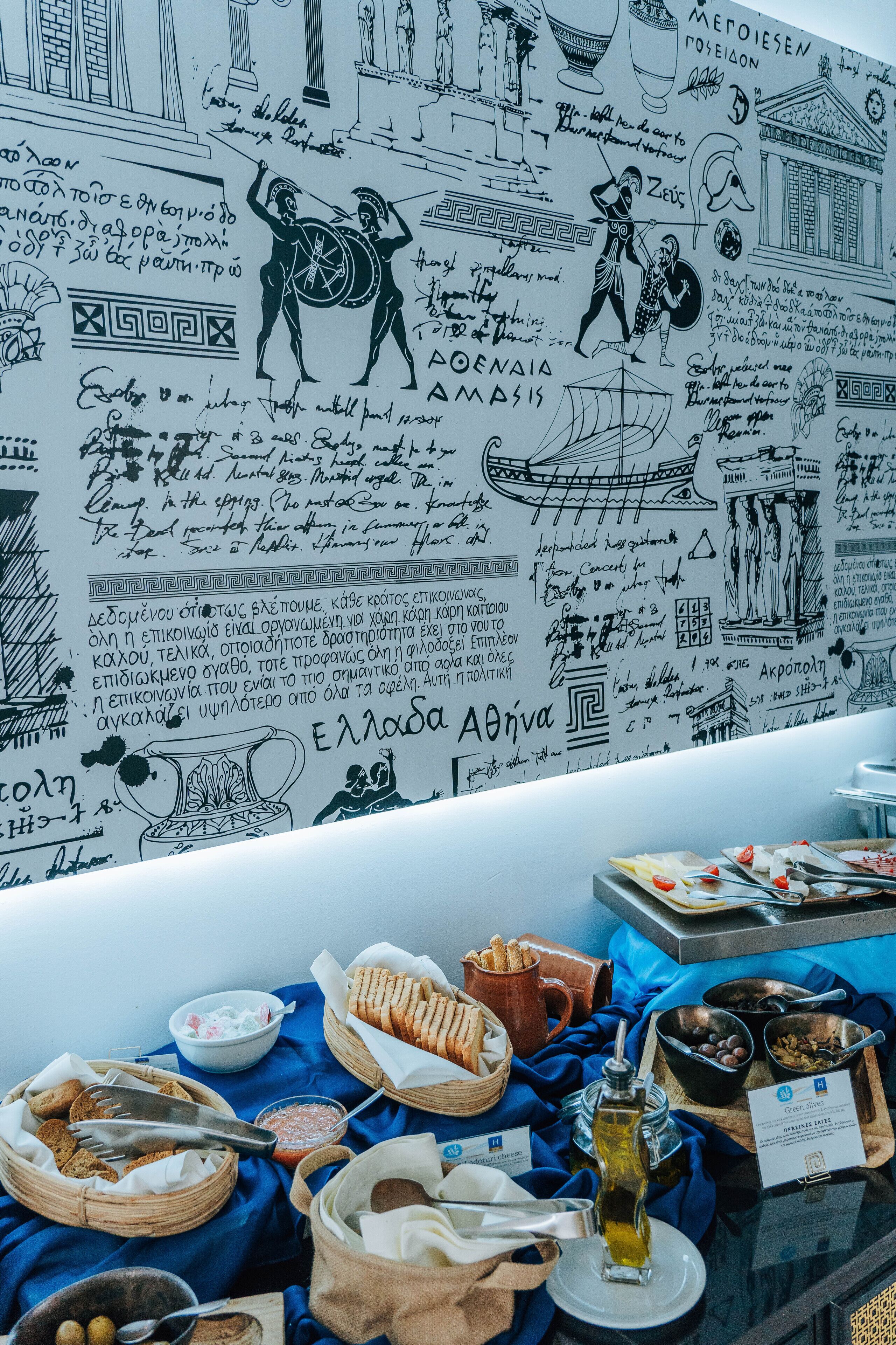 Una habitación con un muro lleno de dibujos y escrituras, una mesa con comida y bebidas, y un paño azul.