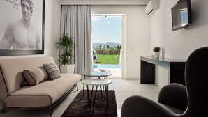 Un salon moderne avec un canapé, une table basse, un téléviseur et une vue sur une piscine et un espace verdoyant.