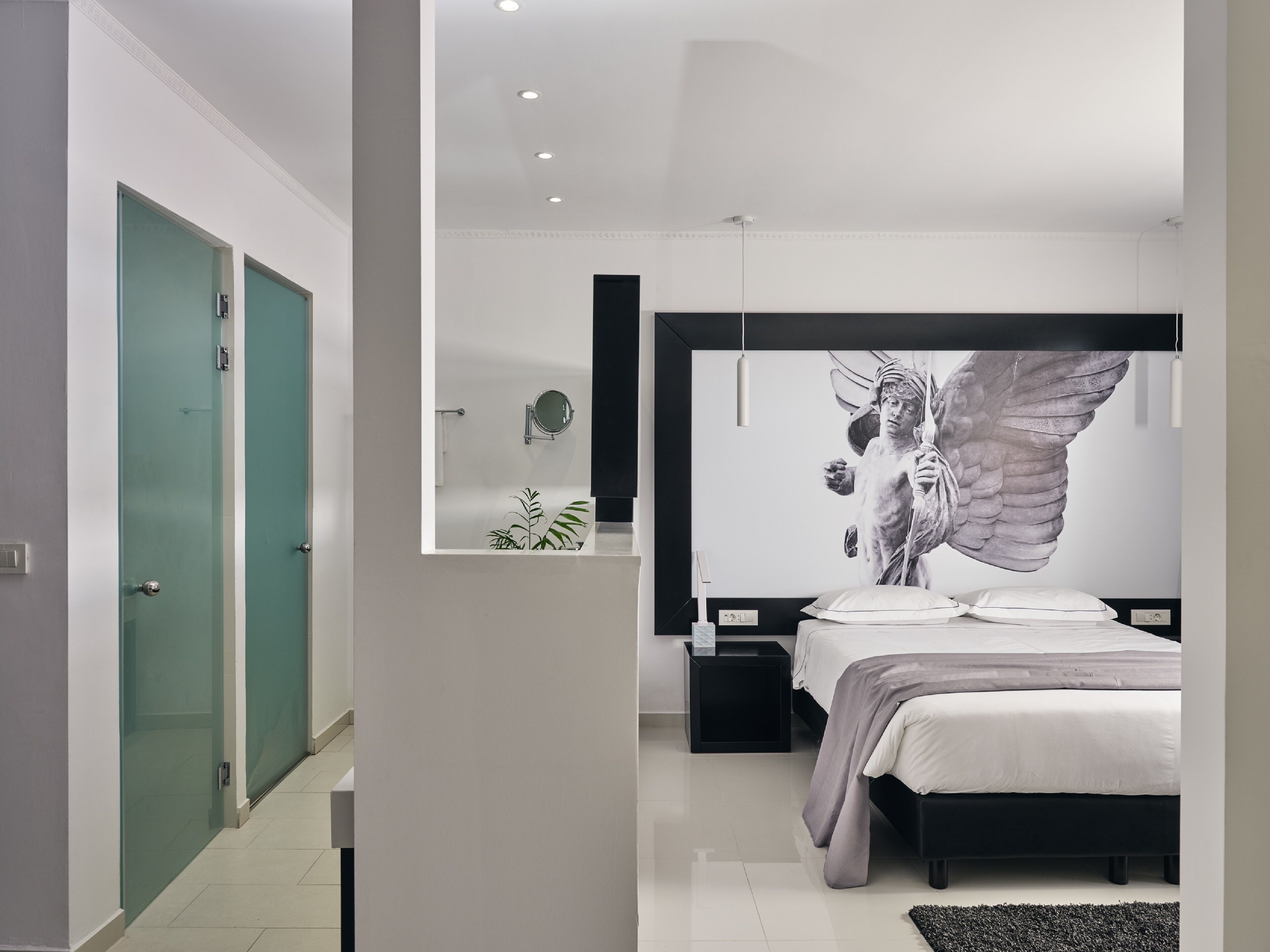 Un dormitorio moderno con una cama grande, una obra de arte colgada en la pared de un ángel y una mesita de noche pequeña.