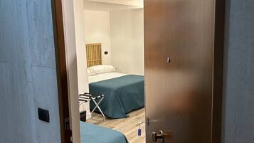 Une chambre avec deux lits, une porte en bois et un plafond blanc.