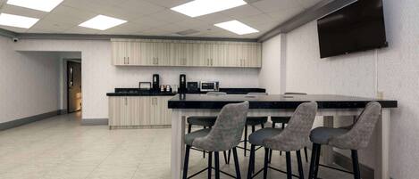 Una cocina moderna con una isla central, taburetes de bar y un televisor de pantalla plana montado en la pared.