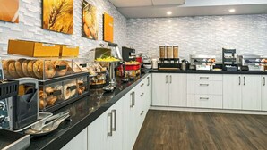 A modern kitchen with white cabinets, a black countertop, and various food items and appliances.