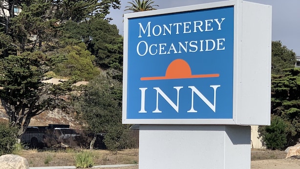 A sign for Monterey Oceanside Inn with a clear view of the surrounding landscape.
