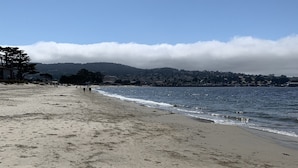 A beach with footprints, a clear sky, and distant hills.