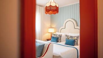 A hotel room with a bed, a nightstand, a lamp, and a hanging light fixture.