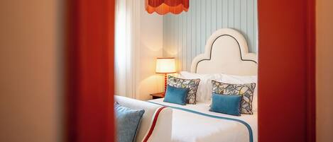 A hotel room with a bed, a nightstand, a lamp, and a hanging light fixture.