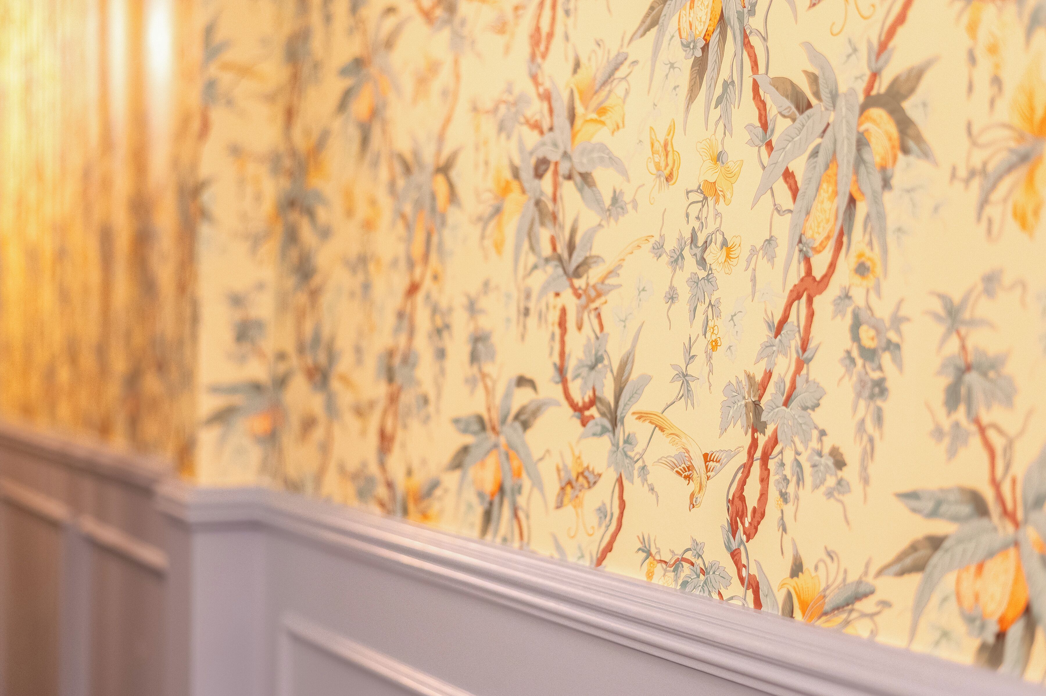 A wall with a floral wallpaper pattern.