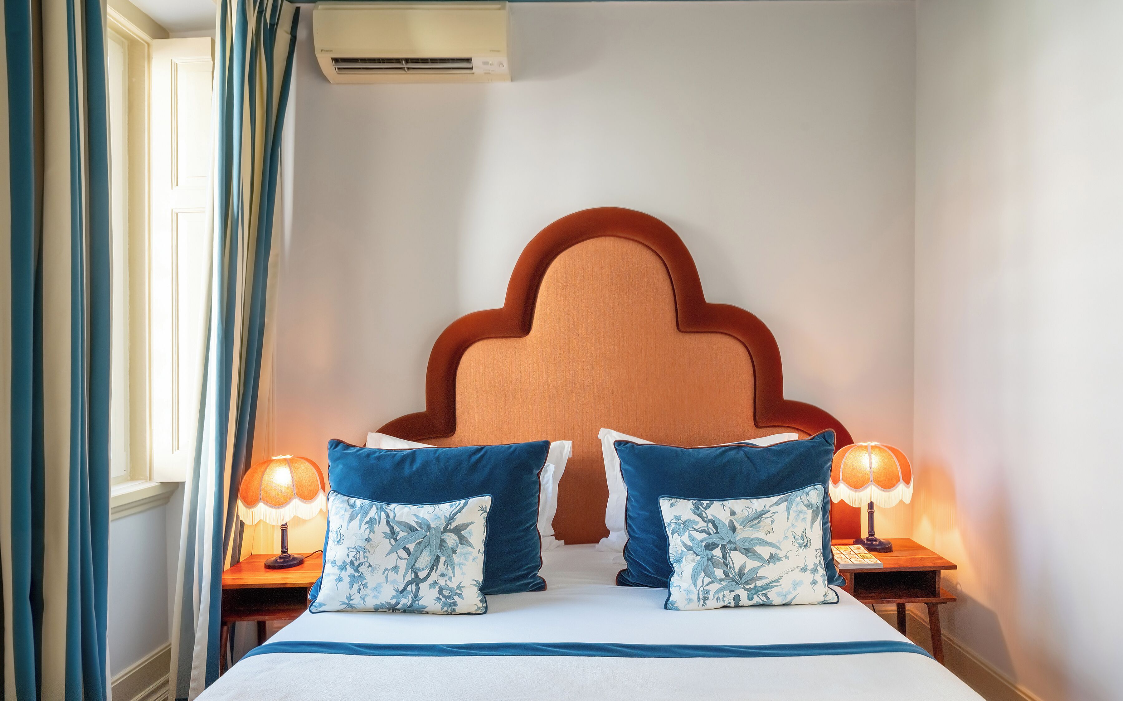 Ein Hotelzimmer mit einem großen Bett, zwei Nachttischlampen und einem dekorativen Kopfteil.