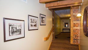 A staircase with a wooden handrail and carpeted steps leading to a room with a brick wall and a mirror. - The Murray Premises Hotel (St. John's)