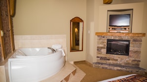 A bathroom with a large bathtub, a stone fireplace, and a television mounted above it. - The Murray Premises Hotel (St. John's)