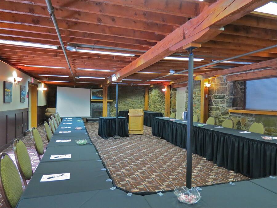 A conference room with a long table, chairs, a projector screen, and stone walls.