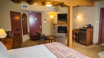 A hotel room with a bed, a fireplace, a television, a desk, and a chair.