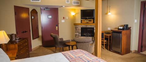 A hotel room with a bed, a fireplace, a television, a desk, and a chair.