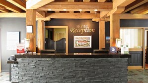 A hotel reception area with a stone counter, wooden ceiling beams, and a framed picture of the hotel. - The Murray Premises Hotel (St. John's)