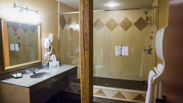 A bathroom with a large mirror, a sink, and a shower area.