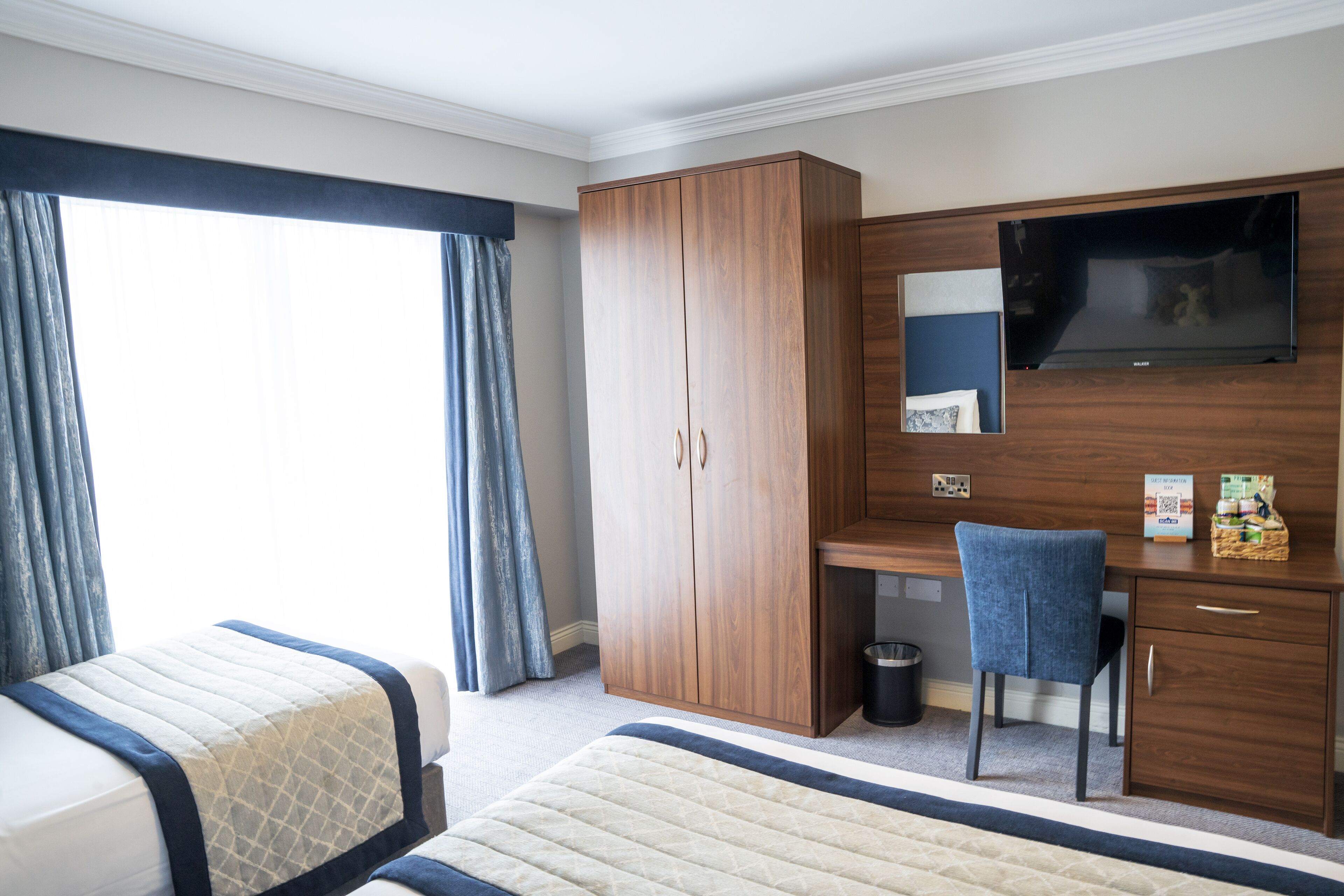 A hotel room with a bed, a desk, a television, and a wardrobe.