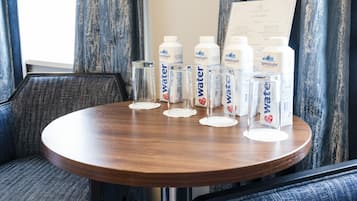Una mesa redonda de madera con botellas de agua y una carta en una habitación de hotel.