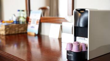 A coffee machine with four purple capsules on a wooden table.