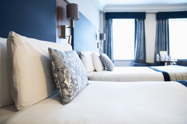 A hotel room with two beds, a large window with curtains, and a desk with a lamp. - The Western Hotel (Galway)