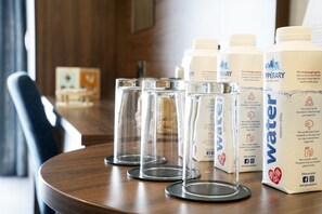 A table with four clear glasses and three water bottles on a wooden table. - The Western Hotel (Galway)