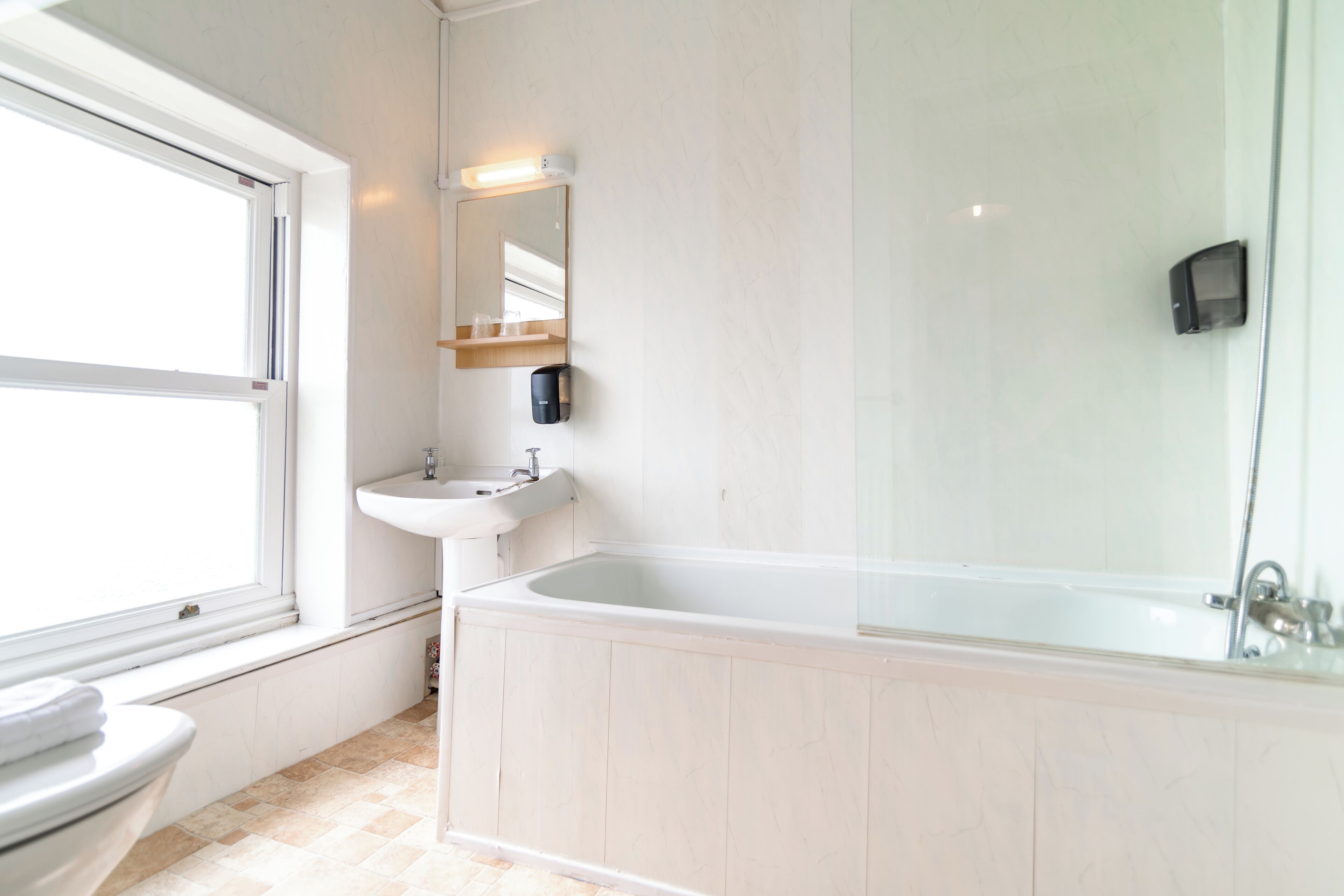 Un baño con ventana, lavamanos y bañera.