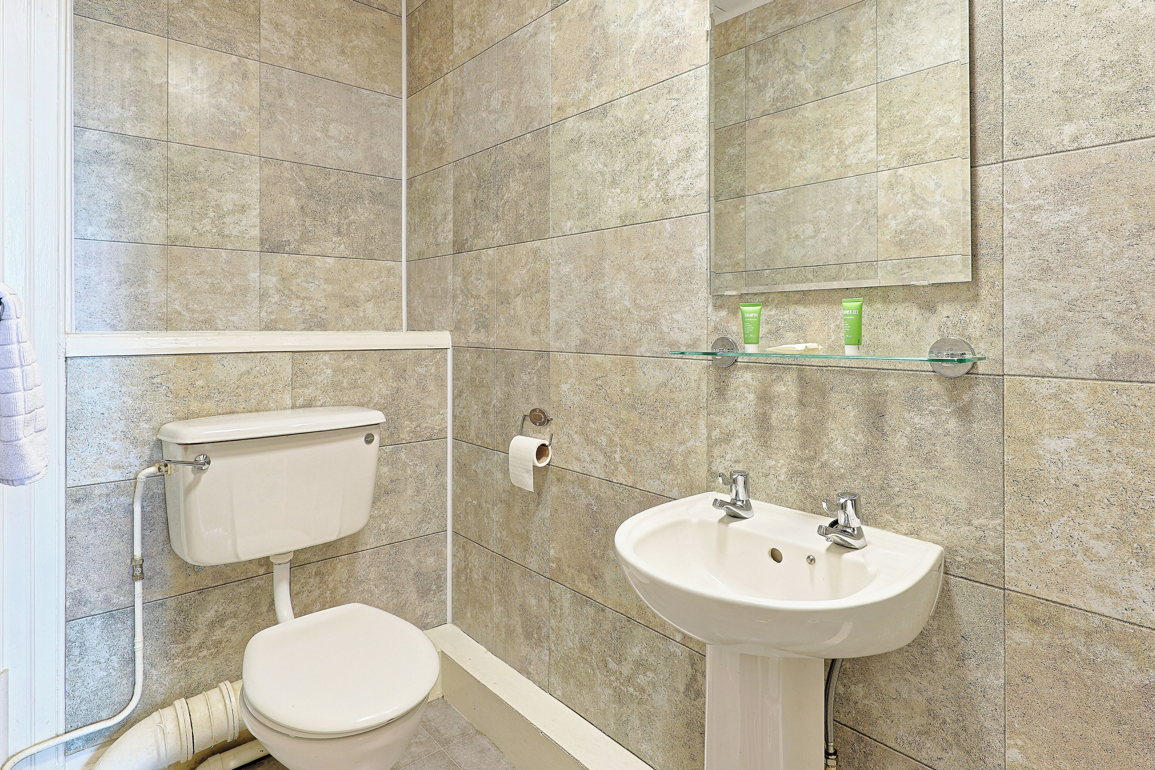 Un bagno con il water, un lavandino e uno specchio sopra il lavandino.