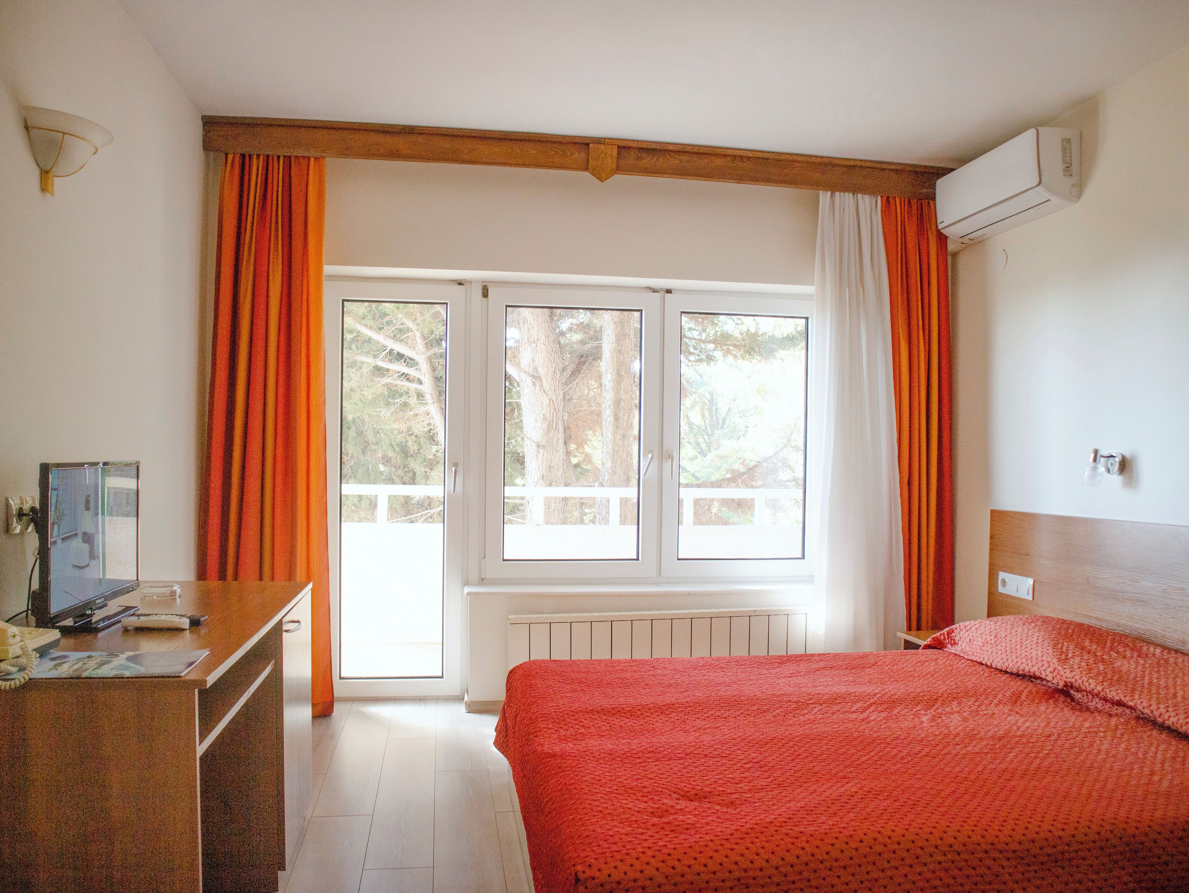 A room with a bed, a desk, and a window with curtains.