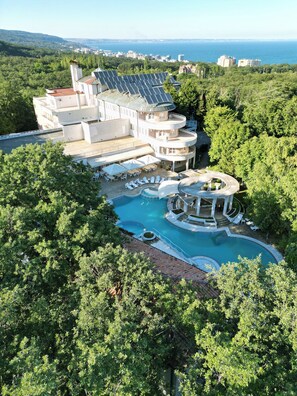 A multi-story building with a pool and outdoor seating area surrounded by trees. - Park Hotel Bellevue (Golden Sands)