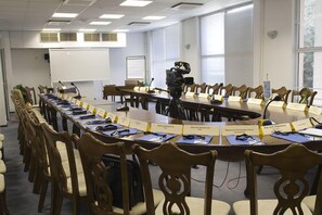 Ein Konferenzraum mit einem langen Tisch, mehreren Stühlen, Namensschildern und einer Kamera auf einem Stativ.