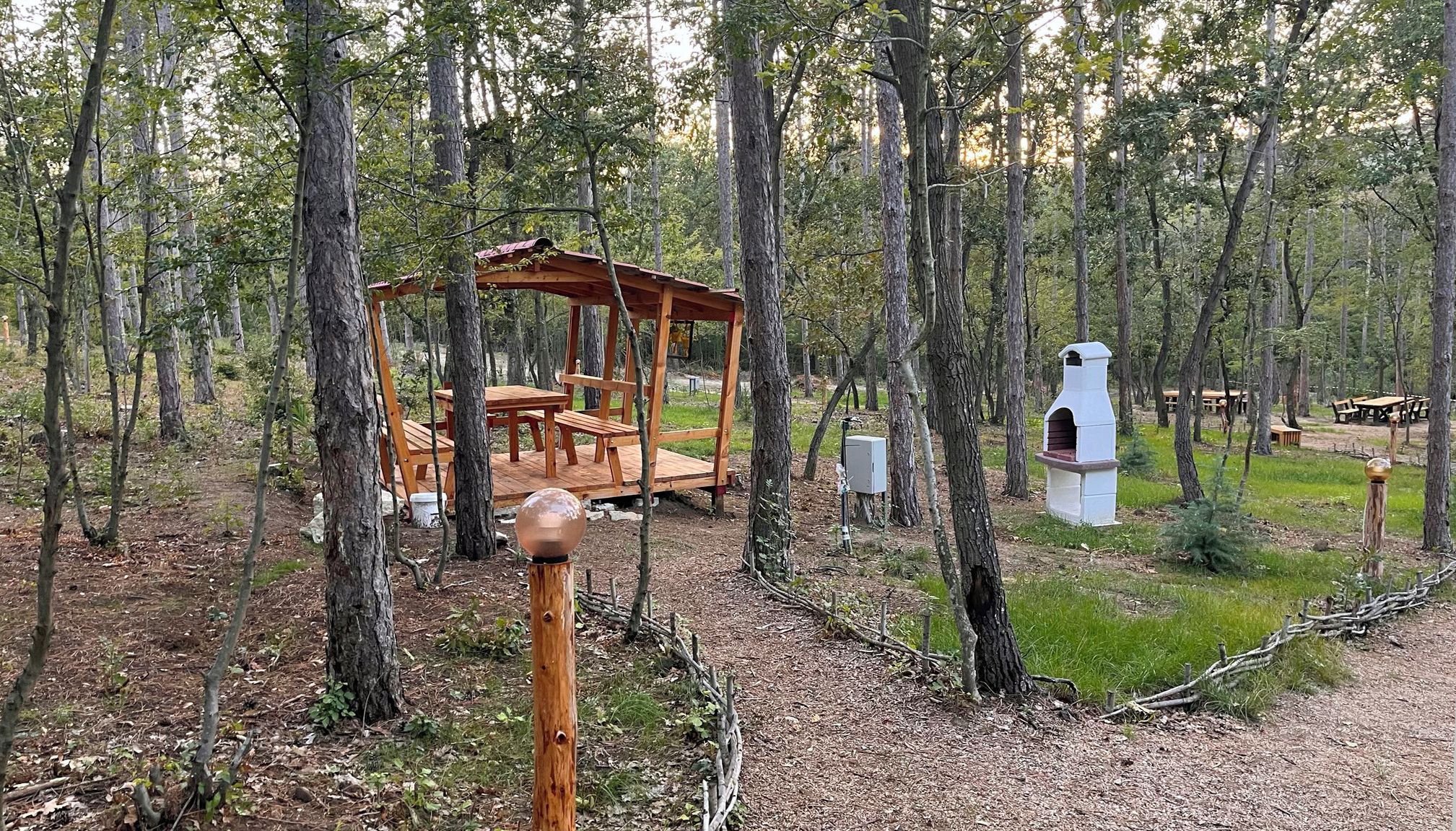 Une zone boisée avec un kiosque en bois et une nichoir blanc.