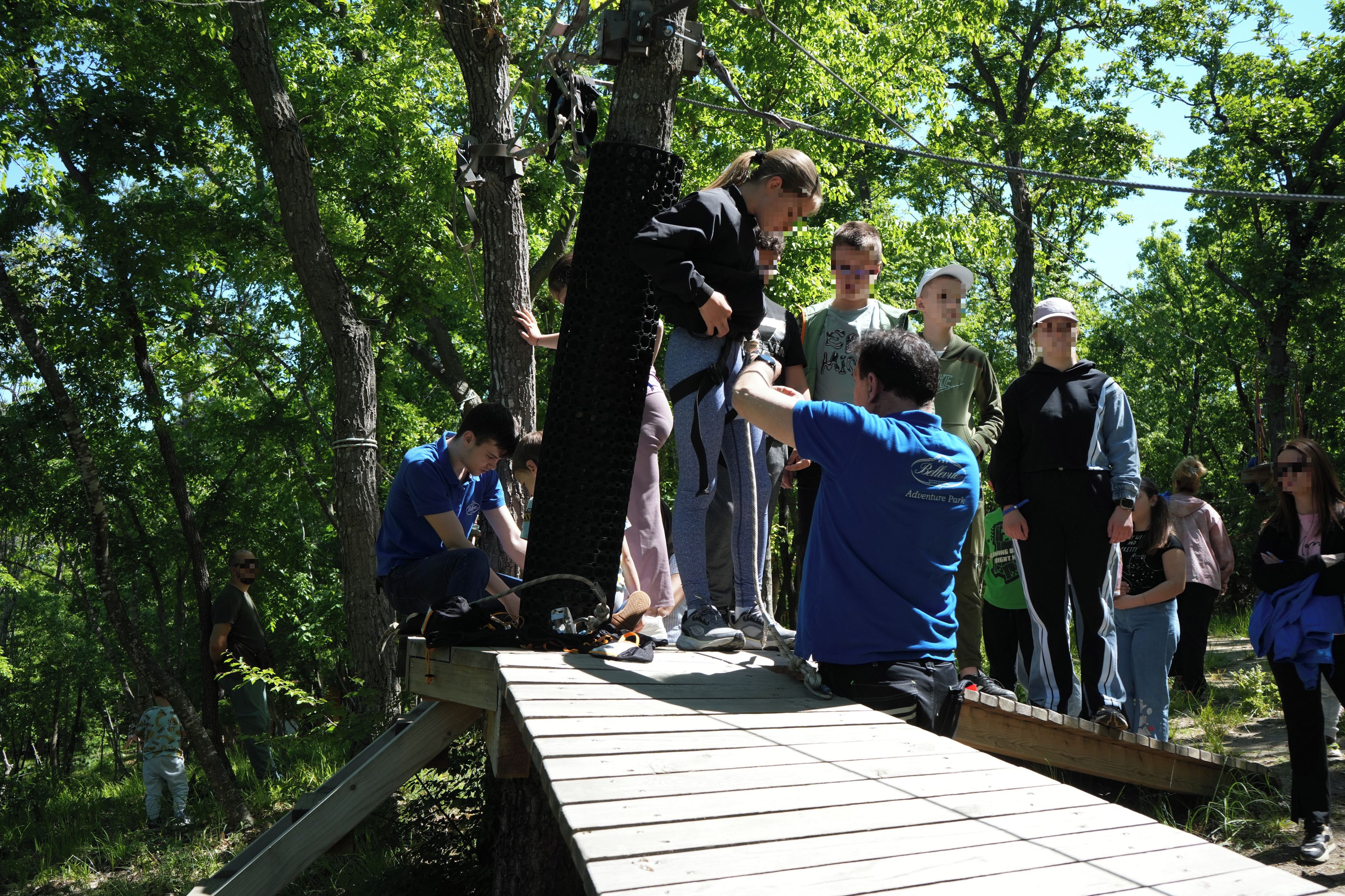 A group of people on a wooden bridge in a wooded area.