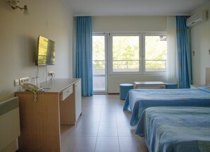 A hotel room with a desk, telephone, and a bed with a blue bedspread. - Park Hotel Bellevue (Golden Sands)
