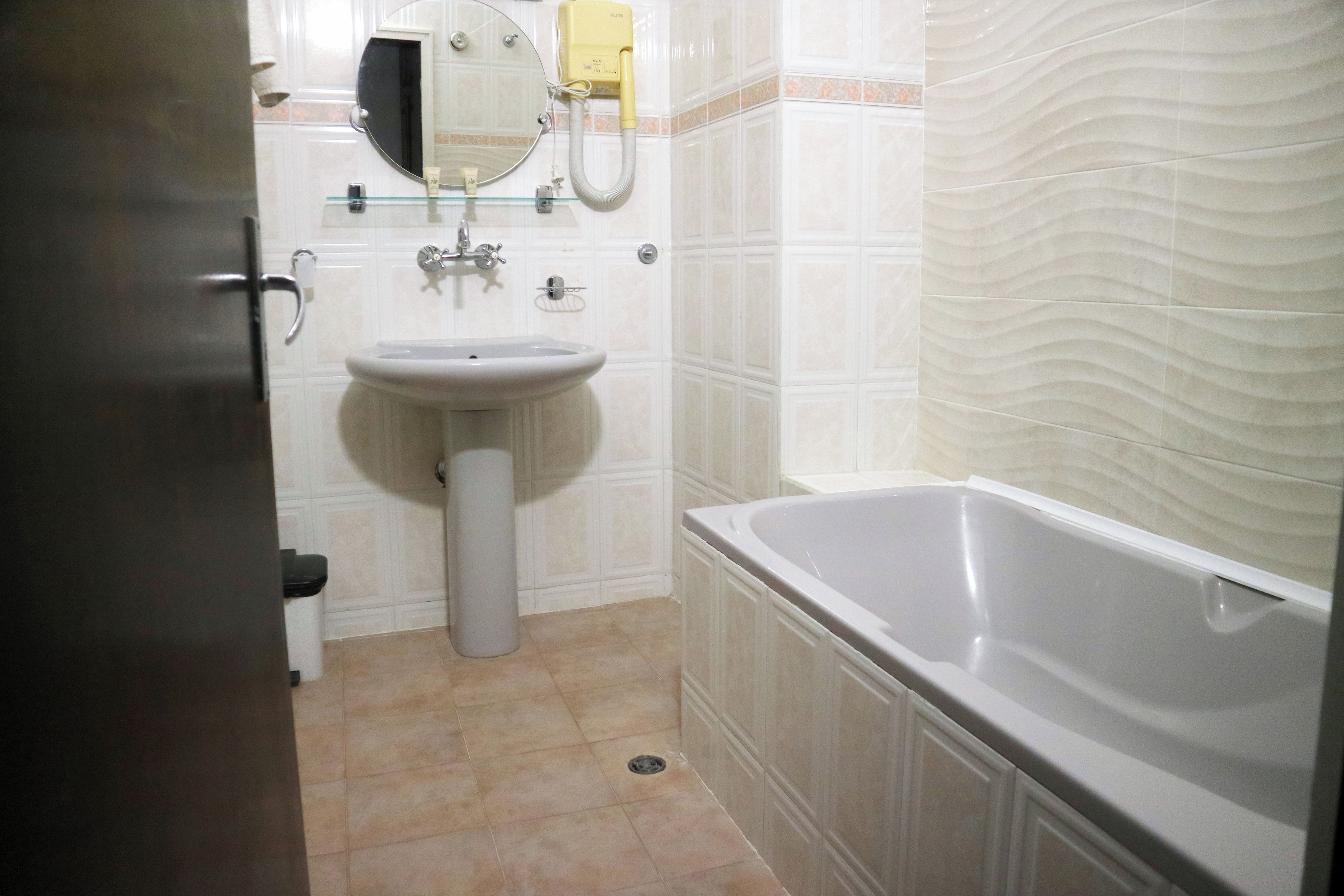 A bathroom with a sink, mirror, and bathtub.