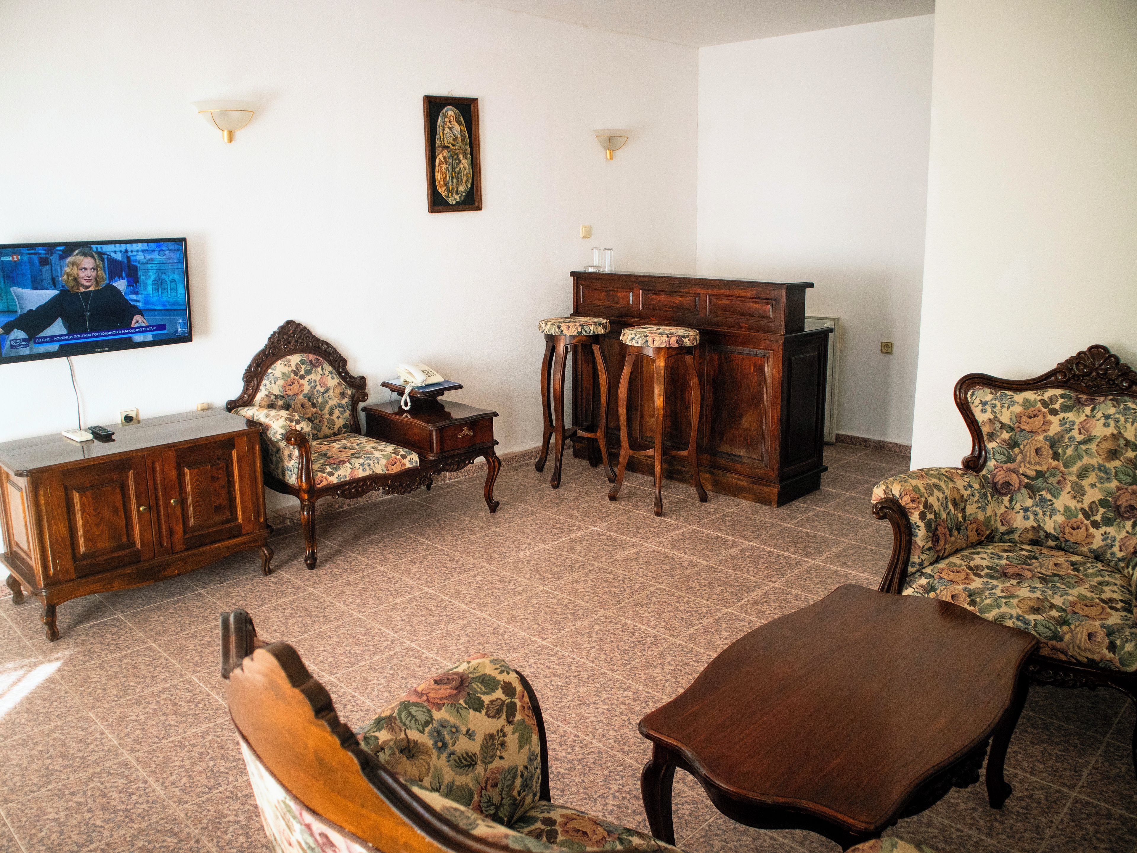 Una sala de estar con televisor, muebles de madera y piso de baldosas.
