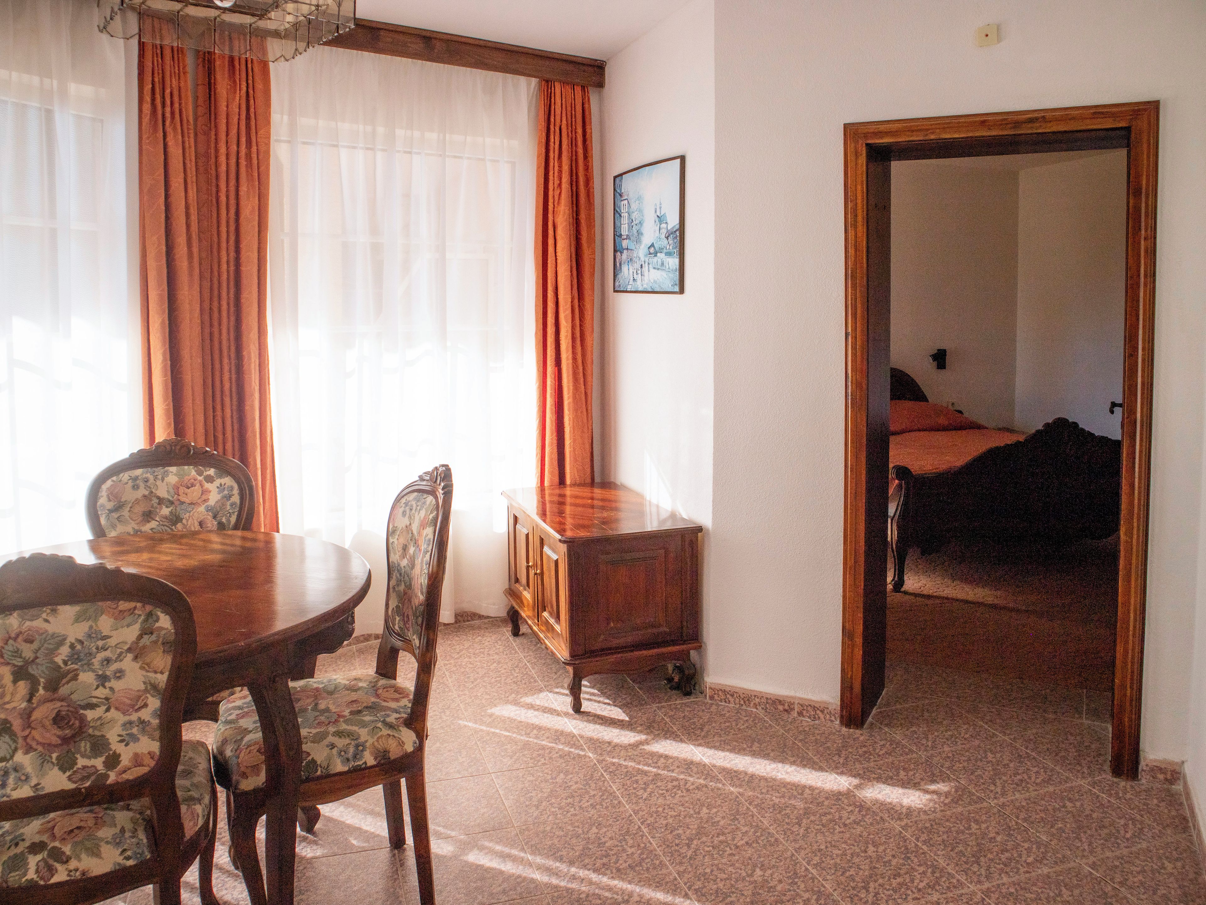 Una habitación con una mesa de comedor, sillas, un armario y una cama.