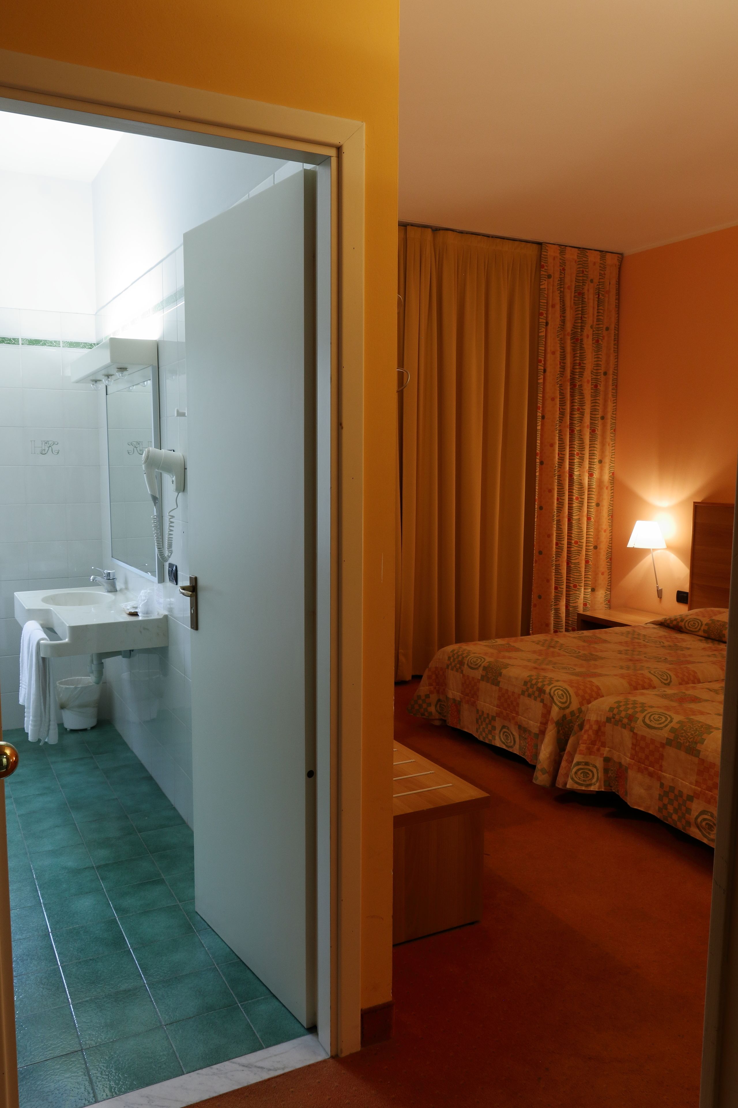 Ein Hotelzimmer mit Bad, Bett, Nachttisch und Lampe.