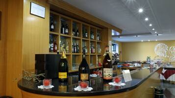 A bar area with shelves of liquor bottles, a counter with glasses and a menu, and a wall with a logo.