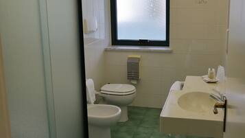 Un baño con inodoro, lavamanos y ventana.