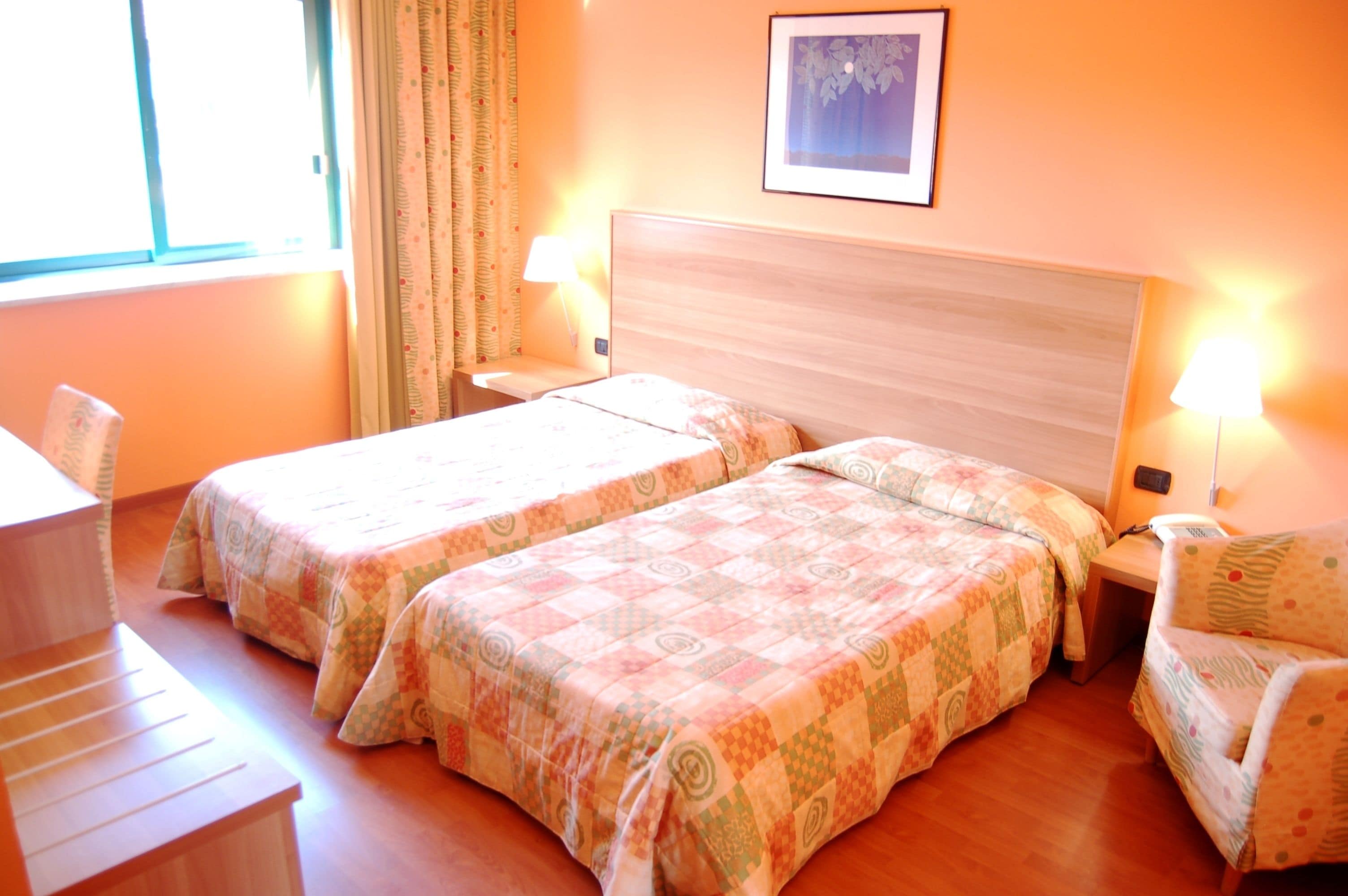 Habitación de hotel con dos camas, un escritorio y una silla.
