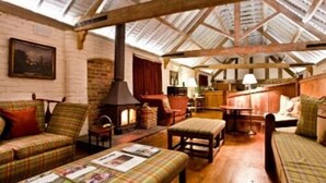 A cozy attic room with a high wooden ceiling, a fireplace, and a rustic wooden bench. - Old Downton Lodge (Ludlow)