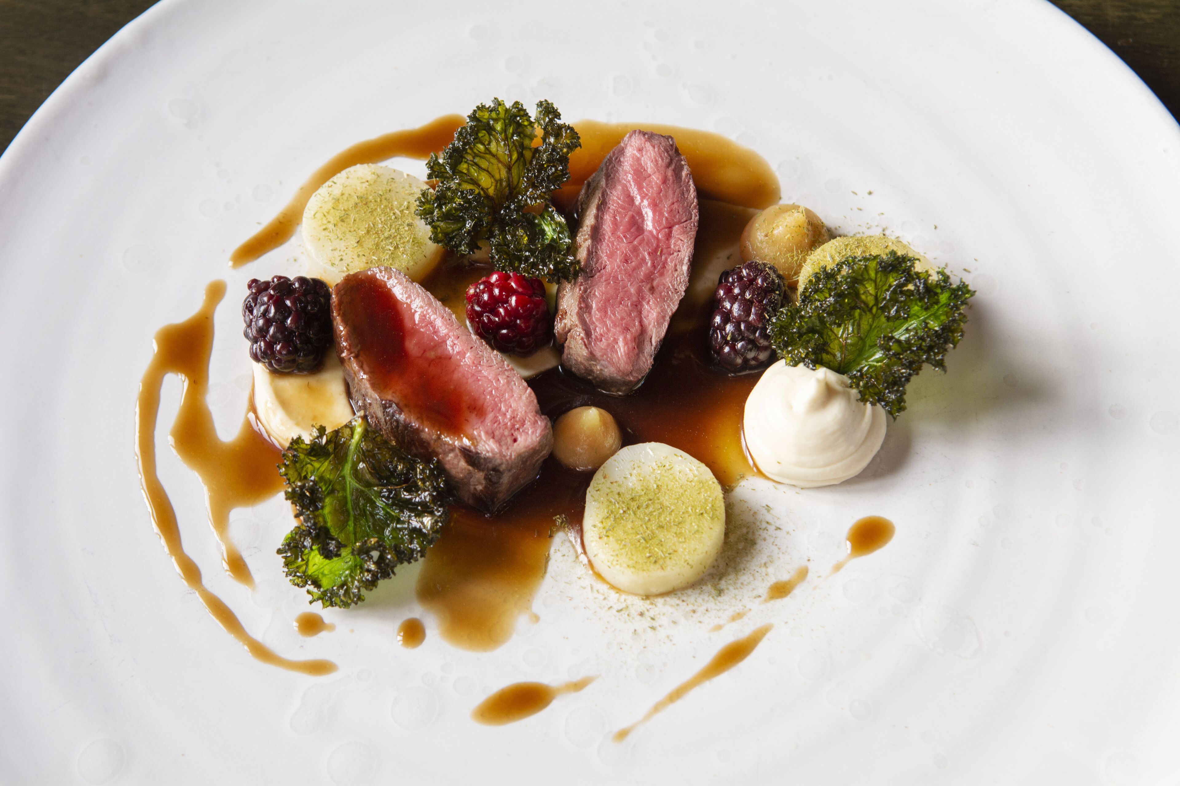 Un plato de comida con varios elementos, incluyendo carne, bayas y verduras.